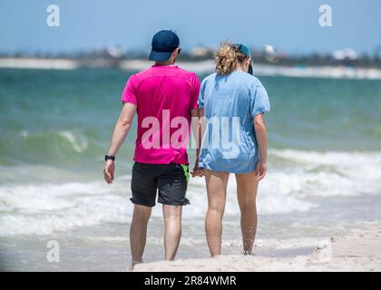 Un jeune couple de derrière marche le long de la plage pittoresque tenant les mains pendant les vacances d'été Banque D'Images