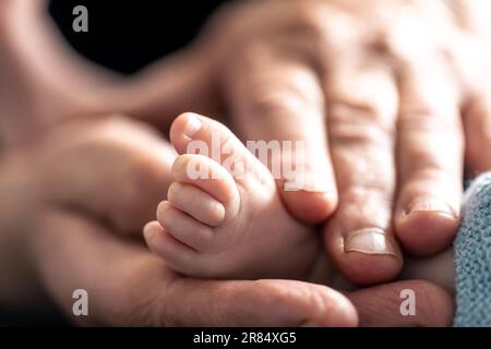 La vieille femme tient les jambes de l'enfant dans ses mains. Banque D'Images