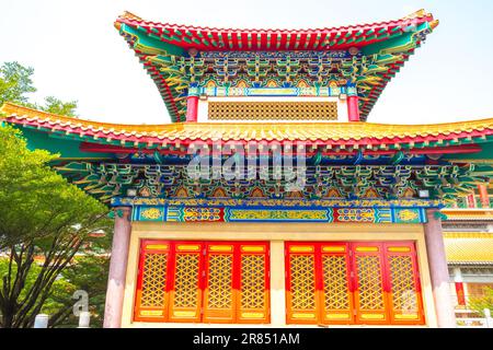 Bâtiment de temple chinois traditionnel orné avec des niveaux de toit colorés vibrants, peinture détaillée de support et portes en treillis rouge doré à la lumière du jour Banque D'Images