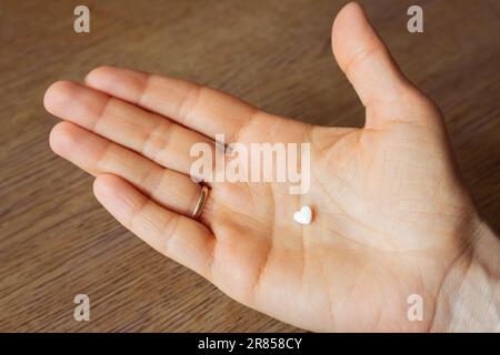 Pilule blanche sur la main ouverte de paume. Pilule en forme de coeur à la main. Traitement médical. Analgésique de l'amour malheureux. Prescription de thérapie. Concept de soins de santé. Banque D'Images
