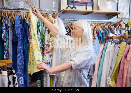 Femme âgée achetant des vêtements durables d'occasion à la boutique de charité d'occasion ou à la boutique de Thrift Banque D'Images