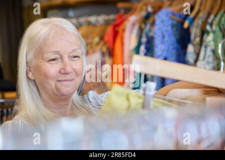 Femme âgée achetant des vêtements durables d'occasion à la boutique de charité d'occasion ou à la boutique de Thrift Banque D'Images