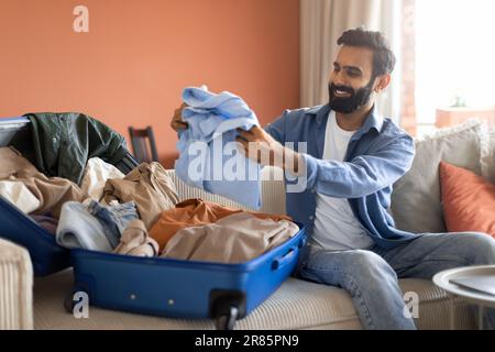 Homme arabe emballage des vêtements en valise préparation des bagages à la maison Banque D'Images