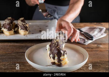 Une femme avec un tablier sert un morceau de banane recouverte de chocolat sur une assiette Banque D'Images