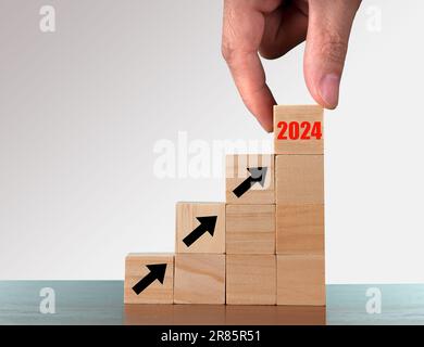 2024 concept d'entreprise de croissance de succès. Cubes en bois de flip main d'homme d'affaires de la nouvelle année 2024 avec plan d'objectifs d'action. Banque D'Images