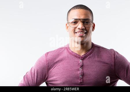 Portrait d'un jeune homme noir joyeux, portant avec élégance des verres à cadre métallique. Une fois considéré comme nerdy dans les 80s et 90s, maintenant considéré comme frais. La mode est un Banque D'Images