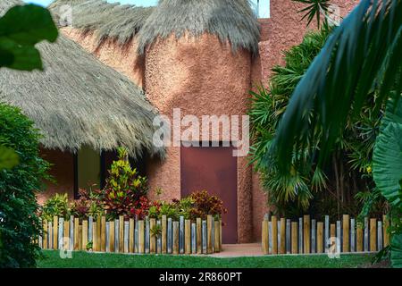 Maison de boue avec un toit de chaume et un beau jardin. Banque D'Images