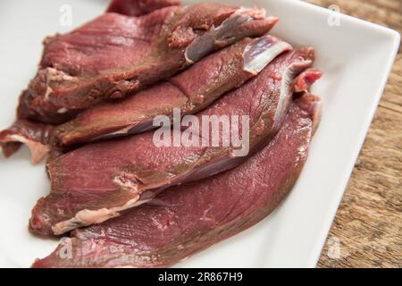 Des tranches de venaison brutes provenant d'un cerf de Virginie sauvage, Capreolus capreolus, sont préparées pour être cuites dans une sauce aux haricots noirs. Angleterre GB Banque D'Images