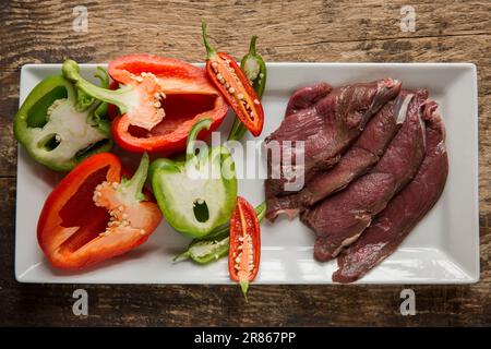 Des tranches de venaison brutes provenant d'un cerf de Virginie sauvage, Capreolus capreolus, sont préparées pour être cuites dans une sauce aux haricots noirs. Angleterre GB Banque D'Images