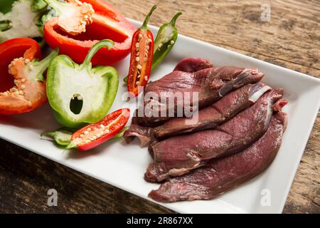 Des tranches de venaison brutes provenant d'un cerf de Virginie sauvage, Capreolus capreolus, sont préparées pour être cuites dans une sauce aux haricots noirs. Angleterre GB Banque D'Images