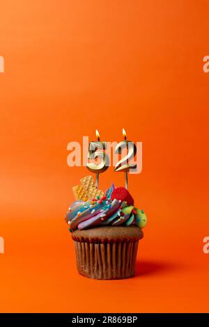 gâteau d'anniversaire avec le numéro 52 - cupcake sur fond orange avec bougies d'anniversaire Banque D'Images