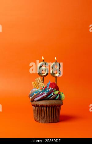 gâteau d'anniversaire avec le numéro 68 - cupcake sur fond orange avec bougies d'anniversaire Banque D'Images