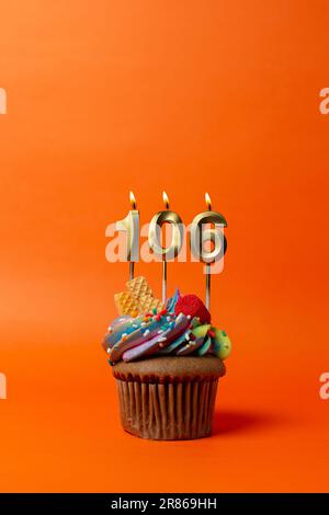 gâteau d'anniversaire avec le numéro 106 - cupcake sur fond orange avec bougies d'anniversaire Banque D'Images