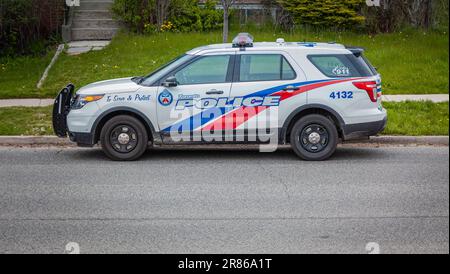 Toronto, Canada, le 17 mai 2020 - Un monospace Ford de police de Toronto blanc aux rayures bleues et rouges garé dans la rue d'un quartier calme Banque D'Images