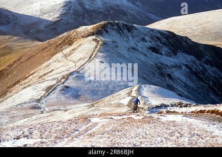 Un motard de montagne descendant un sentier rocheux du sommet de Grisedale Pike vers Sand Hill et Hopehill Head en hiver dans le district de English Lake Banque D'Images