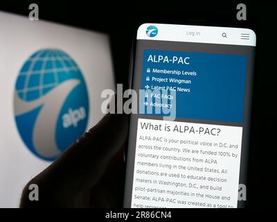 Personne tenant un téléphone portable avec la page web de l'Association internationale des pilotes de ligne aérienne (ALPA) à l'écran avec logo. Concentrez-vous sur le centre de l'écran du téléphone. Banque D'Images