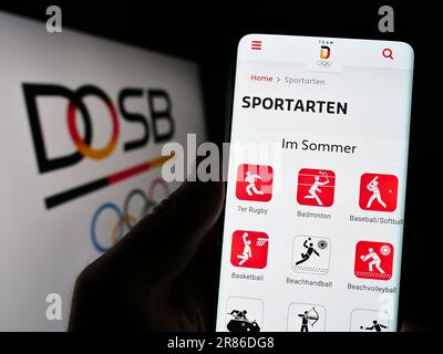 Personne tenant le téléphone portable avec la page web de l'organisation Deutscher Olympicher Sportbund (DOSB) à l'écran avec logo. Concentrez-vous sur le centre de l'écran du téléphone. Banque D'Images