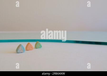 Pilules d'ecstasy de Tesla de couleur orange, verte et bleue en forme de bouclier avec le logo de Tesla; 240 milligrammes de MDMA récréatif ou Molly; drogues Banque D'Images