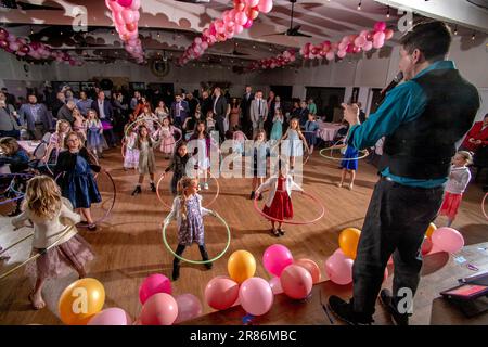 Un maître de cérémonie dirige un groupe de filles avec des hula Hoops à un père et des filles dansant dans une école secondaire catholique de Californie du Sud. Banque D'Images