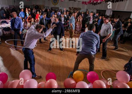 Les pères font tourner les hules hoops dans un père et des filles dansent dans un gymnase catholique de la Californie du Sud. Banque D'Images