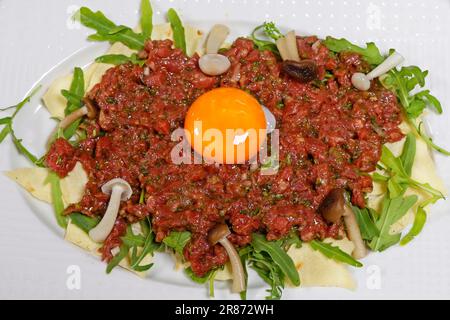 tartare de bœuf traditionnel avec jaune d'œuf et condiments dans une assiette Banque D'Images