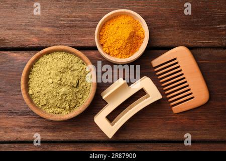 Produits de soins capillaires. Peigne, pince à cheveux, poudre de henné et de curcuma sur table en bois, plat Banque D'Images