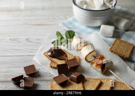 Ingrédients pour un délicieux sandwich avec marshmallows rôtis et chocolat sur table en bois blanc, gros plan Banque D'Images