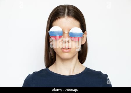 Drapeau de la Russie sur les lunettes d'une fille sur fond blanc, propagande aveugle et trompée de la Russie, ne voit rien à cause de la propagande Banque D'Images