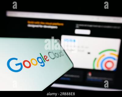 Smartphone avec logo des services informatiques Google Cloud Platform (GCP) à l'écran en face du site Web des entreprises. Mise au point à gauche de l'écran du téléphone. Banque D'Images