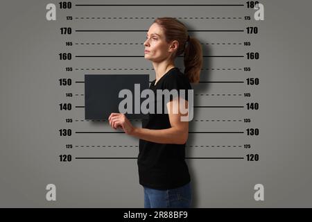 Coup de feu criminel. Femme arrêtée avec une carte vierge contre le tableau de hauteur Banque D'Images