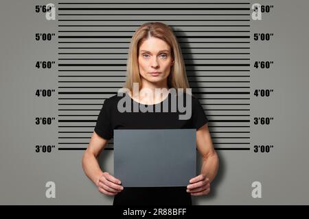 Coup de feu criminel. Femme arrêtée avec une carte vierge contre le tableau de hauteur Banque D'Images