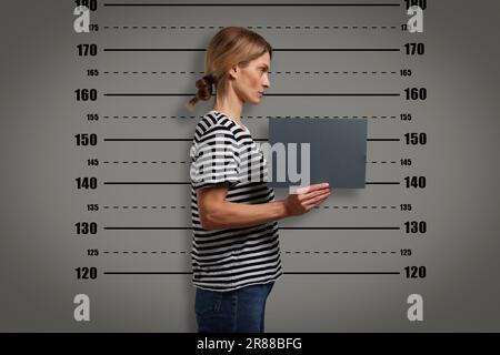 Coup de feu criminel. Femme arrêtée avec une carte vierge contre le tableau de hauteur Banque D'Images