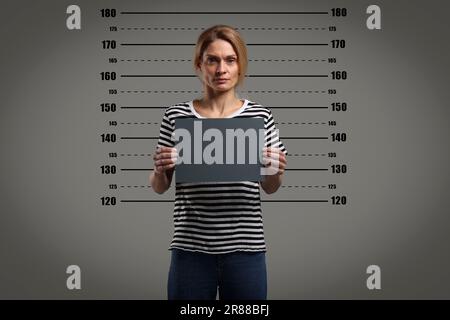 Coup de feu criminel. Femme arrêtée avec une carte vierge contre le tableau de hauteur Banque D'Images