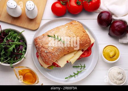 Délicieux sandwich avec une garniture savoureuse et des ingrédients sur une table en bois blanc, plat Banque D'Images