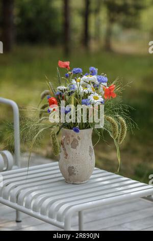Bouquet de fleurs sauvages (cornflowers, chamomiles blé et coquelicots) dans un vase en terre cuite. Variétés de fleurs sauvages et d'herbe. Banque D'Images