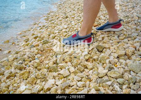 Jambes d'hommes en aquashos sur pierres. Banque D'Images