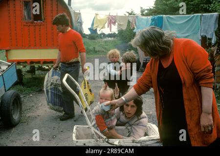 Famille de voyageurs irlandais, grand-mère, mère, père, enfants au bord de la route. Le wagon rouge est un wagon traditionnel en bois tiré par des chevaux. 1979 1970s HOMER SYKES Banque D'Images