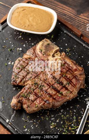 Vue de dessus de T-Bone Steak servi sur une assiette de pierre avec sauce sur le côté Banque D'Images