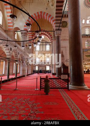 À l'intérieur de la mosquée Suleymaniye à Istanbul, Turquie. Une jeune fille vêtue de vêtements islamiques prie seule. Banque D'Images