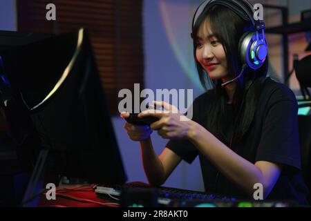 Gamer de cyber hacker féminin utilisant le joystick de la manette pour jouer ou diffuser des jeux sur un ordinateur. Banque D'Images