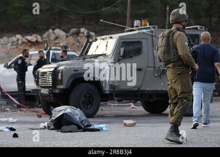 Eli, Israël. 20th juin 2023. Les officiers des forces de sécurité israéliennes gardent près d'un corps d'un agresseur présumé sur les lieux d'une fusillade dans la colonie d'Eli, entre Naplouse et Ramallah, en Cisjordanie. Selon l'armée israélienne, un attaquant palestinien présumé a ouvert le feu sur des civils près d'une station-service, a fait au moins quatre morts et quatre blessés. Crédit : Ilia Yefimovich/dpa/Alay Live News Banque D'Images