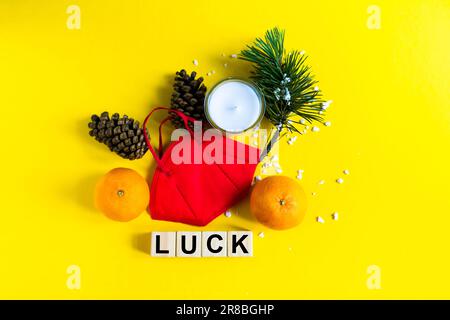 Les mandarines se trouvent dans un masque médical parmi les branches de l'arbre de Noël, mot chance cubes en bois Banque D'Images