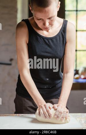 Femme chauve pétrir de la pâte dans la cuisine. Faire du pain. Banque D'Images