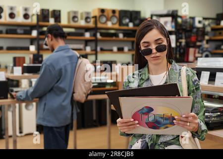 Portrait à la taille de la jeune femme tenant un ensemble de disques en vinyle dans un magasin de musique, espace de copie Banque D'Images