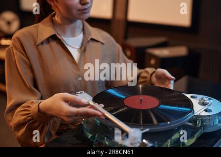 Gros plan de la jeune femme jouant des disques en vinyle à la maison dans un cadre confortable, espace de copie Banque D'Images