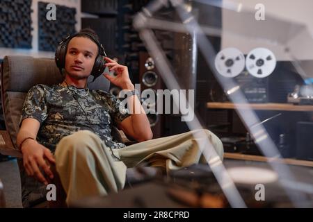 Portrait d'un jeune homme écoutant des disques vinyles à la maison et appréciant la qualité sonore Banque D'Images