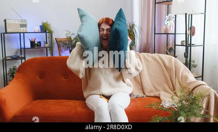 Travaux de réparation aux voisins. Femme irritée fille se relaxant sur les oreilles de couverture de canapé avec des oreillers ennuyé par les voisins bruyants souffrent de maux de tête désir silence. Parois fines à plat sans isolation phonique Banque D'Images