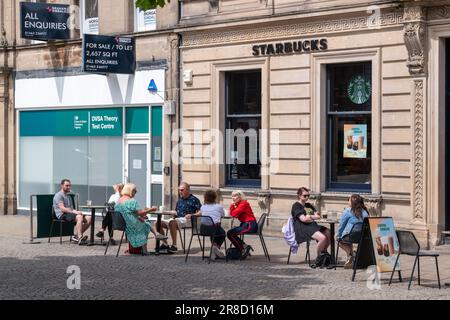 20 juin 2023. High Street, Elgin, Moray, Écosse. Il s'agit de personnes qui ont un café et qui s'asseoir à l'extérieur de Starbucks. Banque D'Images