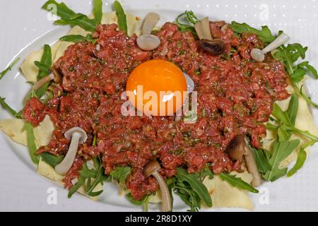 tartare de bœuf traditionnel avec jaune d'œuf et condiments dans une assiette Banque D'Images