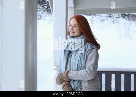 Belle jeune femme dans un belvédère en bois pendant une journée enneigée à l'extérieur. Vacances d'hiver Banque D'Images